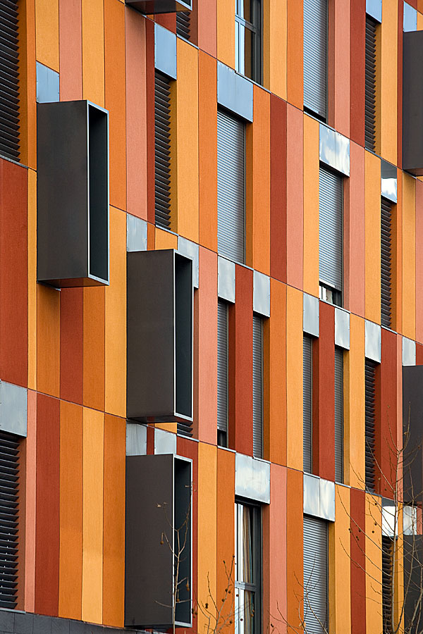 Fotografía de detalle de fachada de edificio de viviendas sociales de nueva arquitectura y tonos naranjas