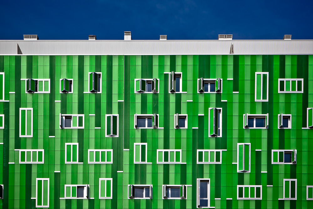 Fotografía de un edificio de viviendas con la fachada compuesta de planchas de plástico en distintas tonalidades de verde