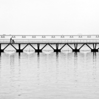 Vista en blanco y negro de la pasarela con el puente Vasco de Gama al fondo.