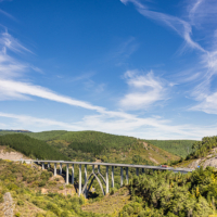 Se el viaducto al fondo del valle, bajo un cielo azul.