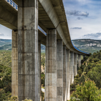 Imagen del viaducto sobre la verde vegetaci&oacute;n y bajo un cielo azul con algunas nubes.
