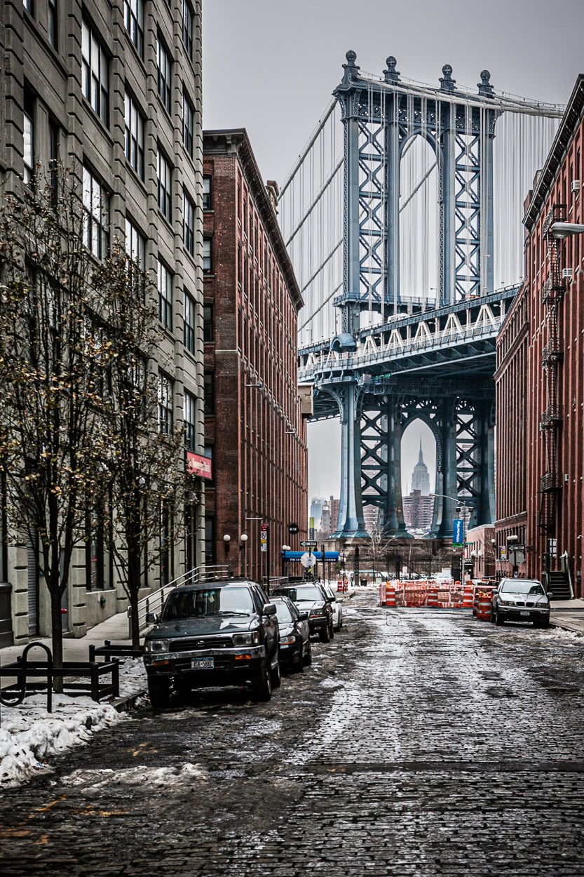 Calle de NY con restos de nievo y el puente de Manhattan al fondo.