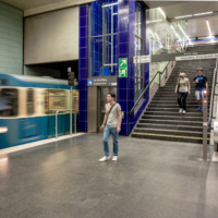 Imagen del interior de la estaci&oacute;n con un tren llegando a la estaci&oacute;n y algunas personas bajando las escaleras.
