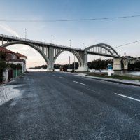 Imagen completa del puente al atardecer, con una carretera en primer plano.