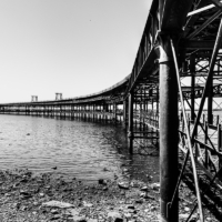Imagen en blanco y negro en la que la silueta del muelle recorre la foto en curva.