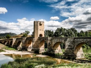 Fotografía del imponente puente de sillares y con una torre fortificada en el medio, sobre un río Ebro que no lleva demasiada agua